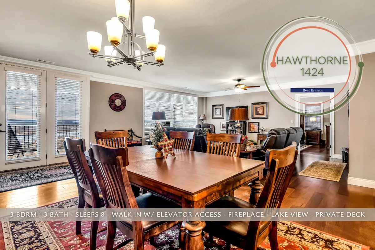 A welcoming dining area with a stylish table set beneath a modern chandelier, situated next to expansive windows offering direct lake views. The electric fireplace adds ambiance, while the layout encourages togetherness for family meals, game nights, or relaxed conversations—all with the ever-present backdrop of the water.