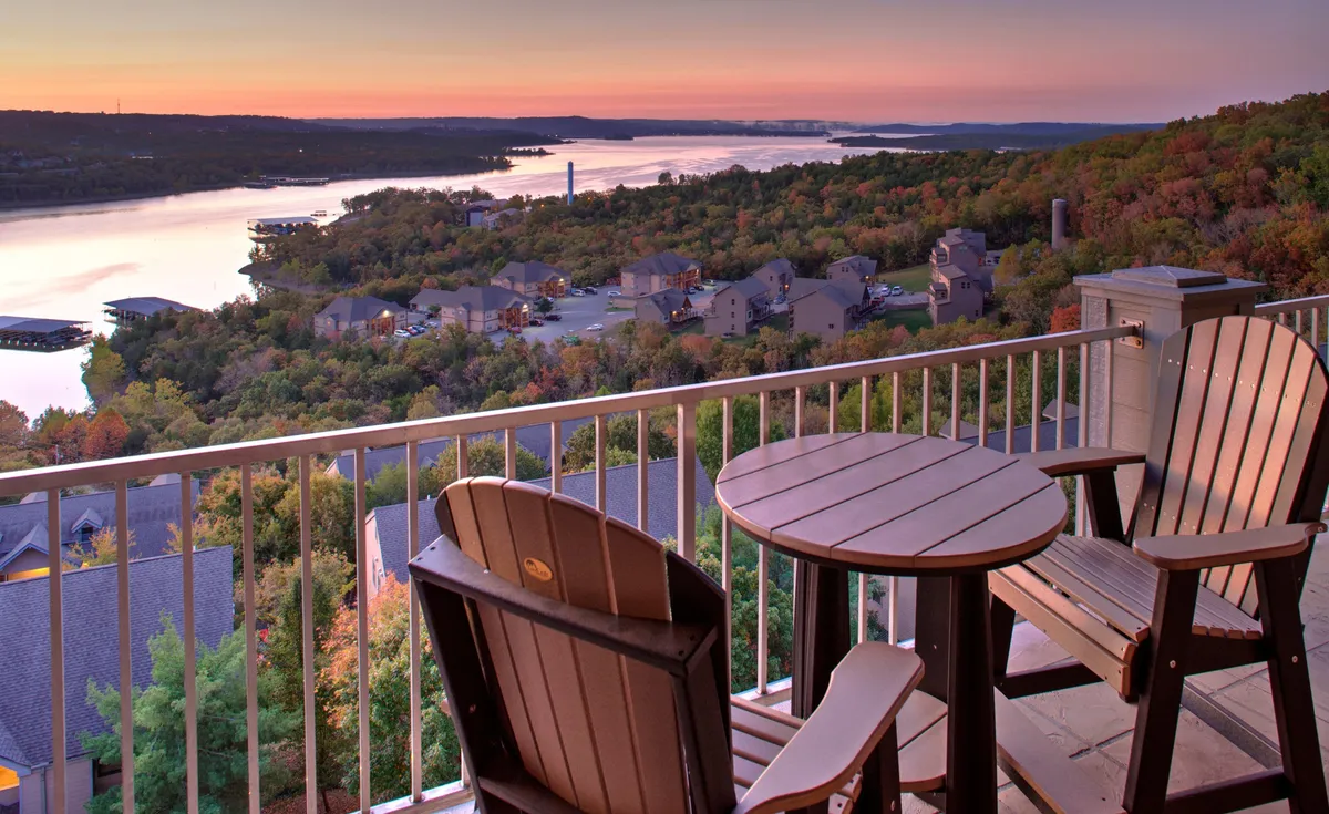 The hero image showcases a serene balcony with comfortable seating, overlooking a tranquil lake bathed in sunset colors. The panoramic view stretches across the water, inviting guests to relax, sip coffee, and soak in the breathtaking natural beauty. Wildlife may be spotted, and the setting is perfect for stargazing as evening falls.