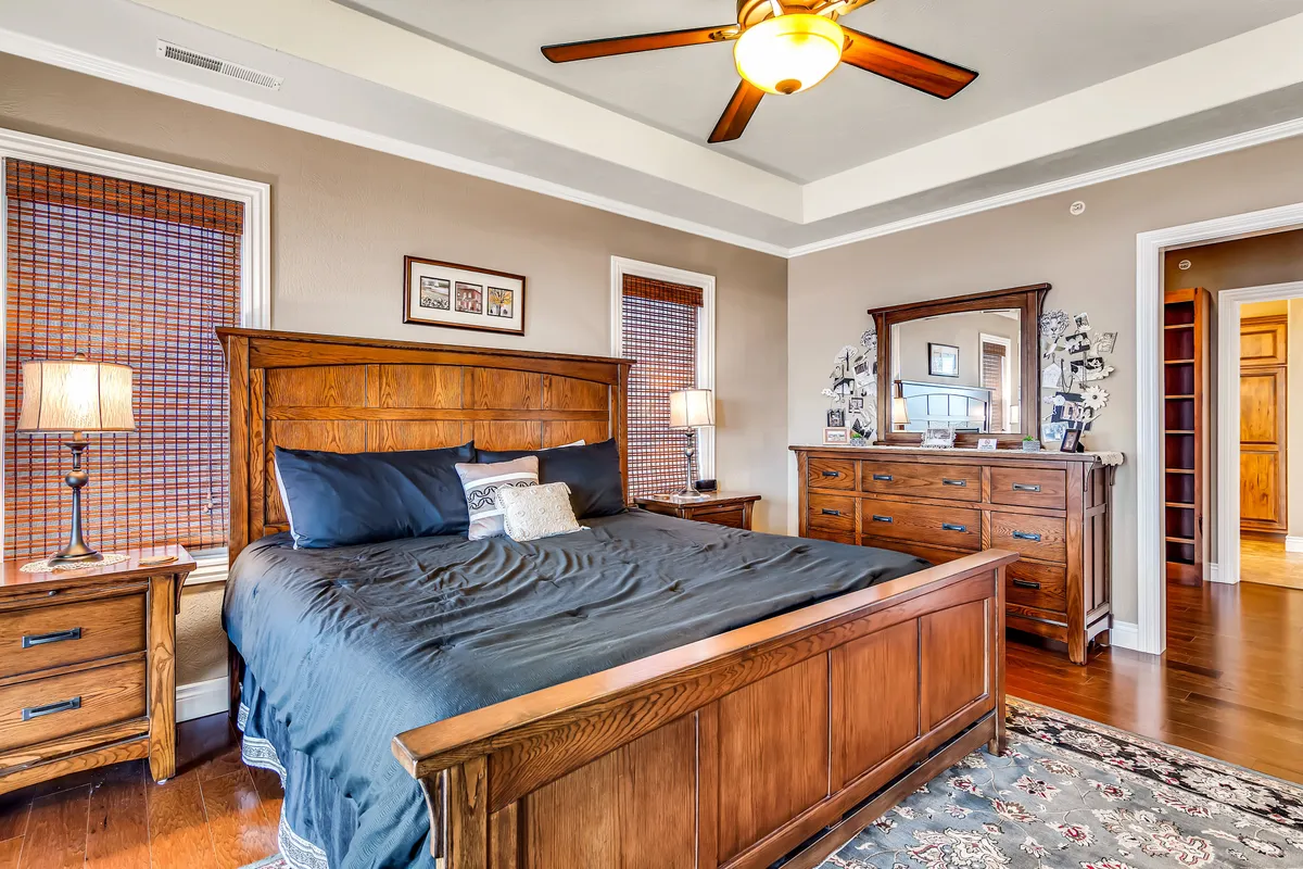 A serene bedroom featuring a wooden bed frame, nightstands with lamps, a dresser with mirror, and decorative wall art. The space exudes calmness with soft lighting and a well-organized layout, perfect for restful nights.