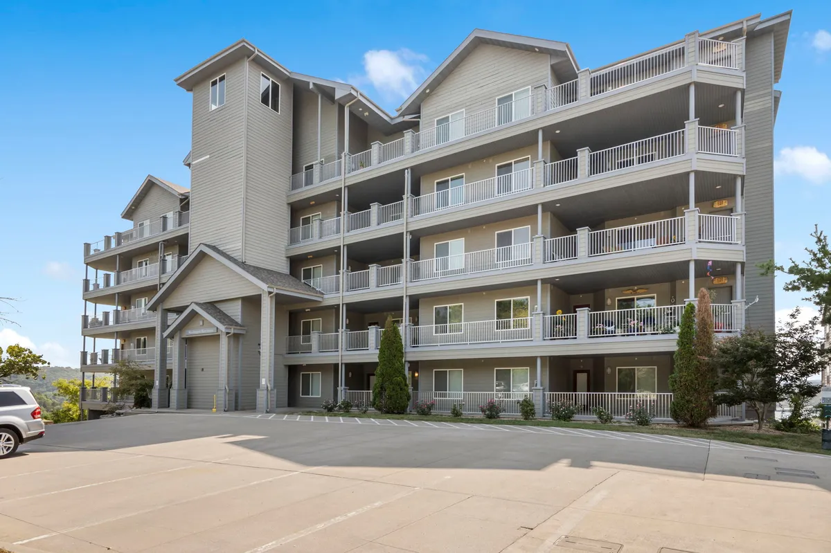 The image showcases the main entrance of the condo building, highlighting the step-free access from the parking area, visible balconies, and the overall inviting architectural details. The approach to the entrance is unobstructed and accessible, reinforcing convenience for individuals with mobility needs or families with strollers.