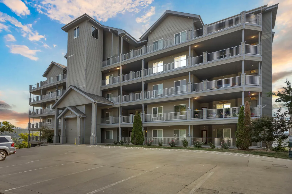 The photo focuses on the exterior of a multi-story building with accessible balconies and a landscaped entry. The overall mood is welcoming and serene, conveying a sense of easy, step-free access to the property.